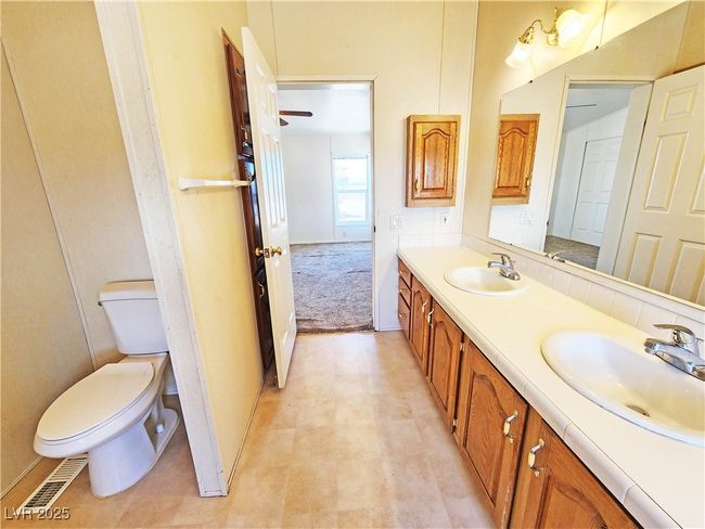 Bathroom featuring visible vents, toilet, double vanity, and a sink | Image 25