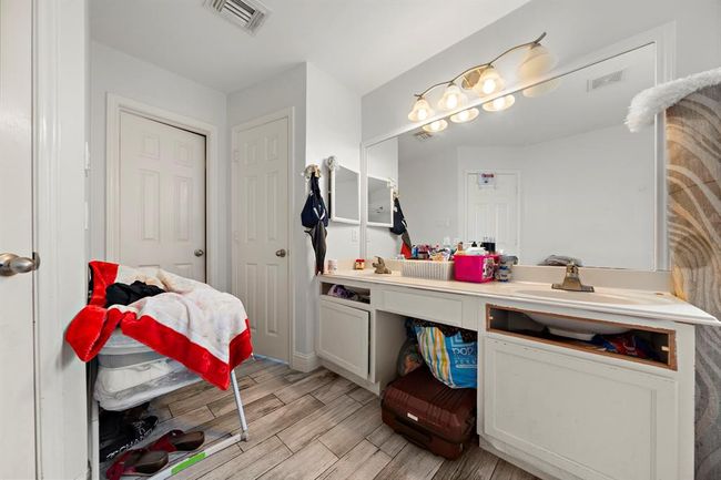 This well-appointed primary suite combines comfort and utility with a spacious bedroom layout and a bright ensuite bath. The bathroom is designed for convenience, featuring dual sinks, a spacious tub, and a separate walk-in shower, all finished with neutral tones and easy-to-maintain surfaces. | Image 20