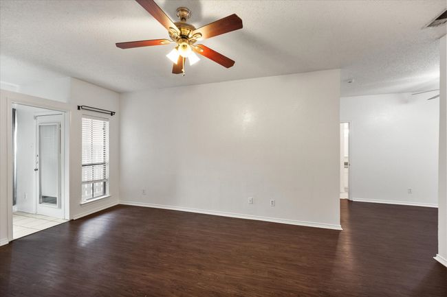Empty room with ceiling fan, wood finished floors, and a textured ceiling | Image 8
