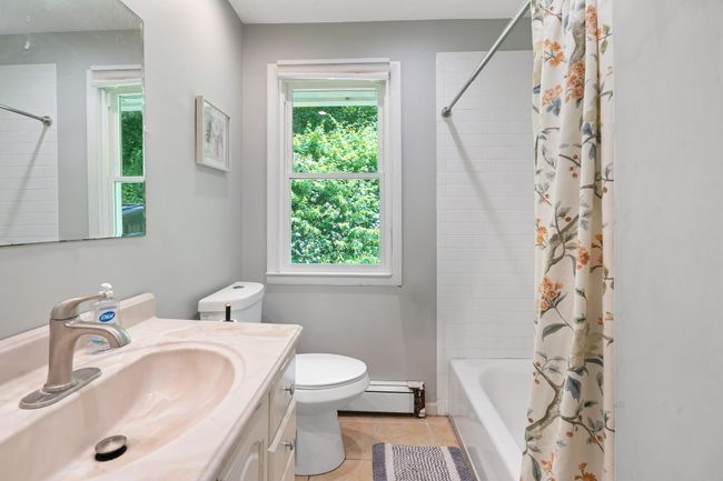 Full bath with a baseboard heating unit, vanity, toilet, and plenty of natural light | Image 29