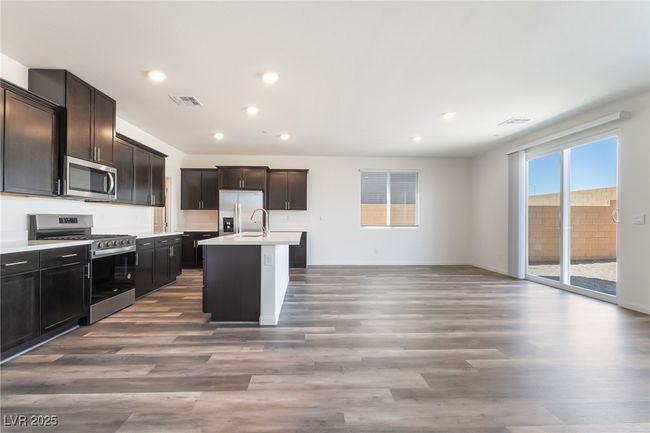 Kitchen featuring stainless steel appliances, light countertops, wood finished floors, recessed lighting, and a kitchen island with sink | Image 7