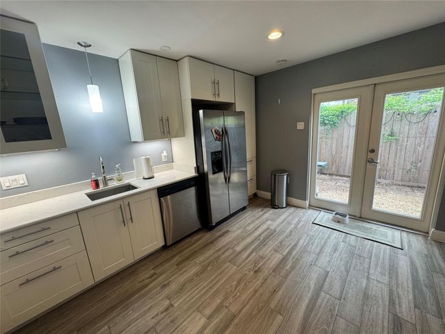 Kitchen with stainless steel appliances, a sink, light wood finished floors, light countertops, and french doors | Image 5