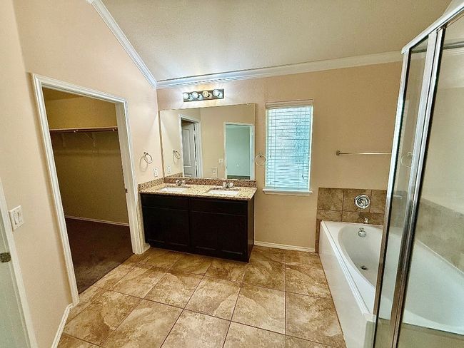 Bathroom with crown molding, double vanity, a garden tub, a shower stall, and a spacious closet | Image 11