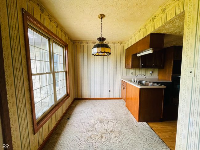 kitchen with a sink, wallpapered walls, plenty of natural light, baseboards, and light countertops | Image 8