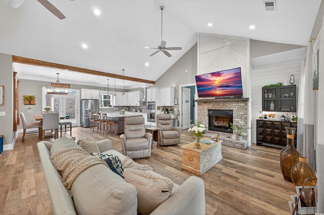 Living area with a ceiling fan, high vaulted ceiling, light wood finished floors, a fireplace, and recessed lighting | Image 16