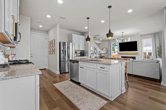 Kitchen with dark wood-style flooring, white cabinetry, appliances with stainless steel finishes, open floor plan, and recessed lighting | Image 14