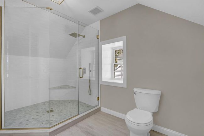 Full bath with baseboards, toilet, wood finished floors, vaulted ceiling, and a shower stall | Image 22