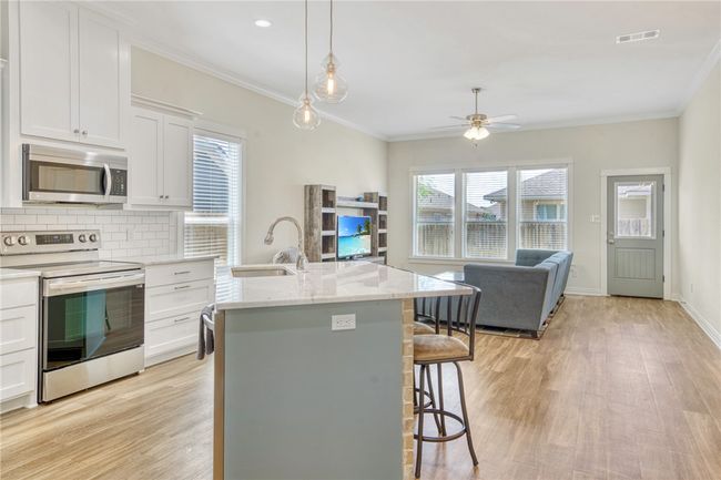 Kitchen featuring appliances with stainless steel finishes, ceiling fan, light wood-style floors, a breakfast bar, and tasteful backsplash | Image 7