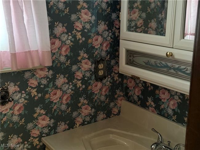 Details with a sink, a bath, and wallpapered walls | Image 29