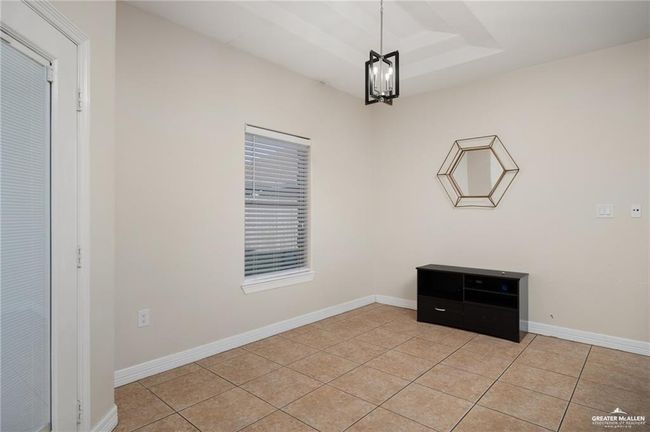 Spare room with light tile patterned floors, a chandelier, and a raised ceiling | Image 8