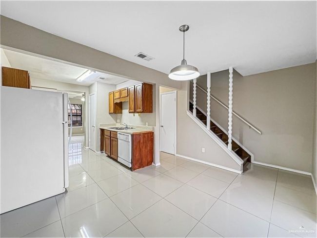 Kitchen with decorative light fixtures, white appliances, sink, and light tile patterned floors | Image 11