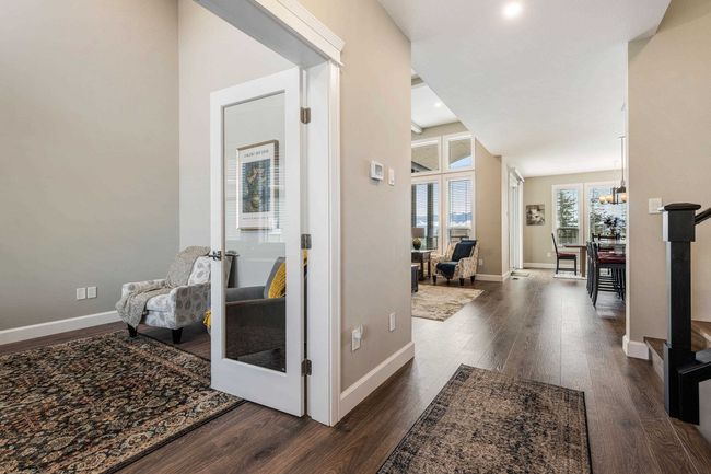Hall with an inviting chandelier, dark wood-style floors, and baseboards | Image 9