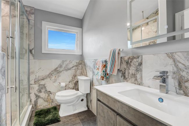 Full bath with tile walls, toilet, a marble finish shower, vanity, and tile patterned floors | Image 22