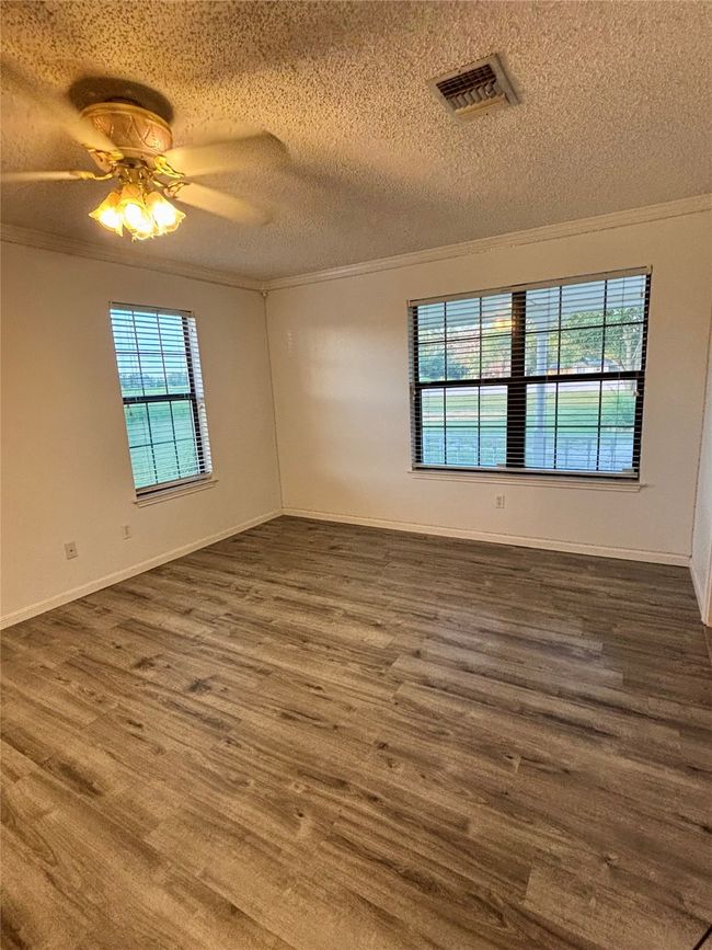 Spare room with ornamental molding, a textured ceiling, dark wood-style floors, and ceiling fan | Image 18