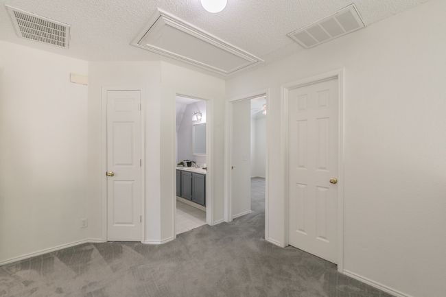 Spare room featuring attic access, visible vents, a textured ceiling, and carpet flooring | Image 14