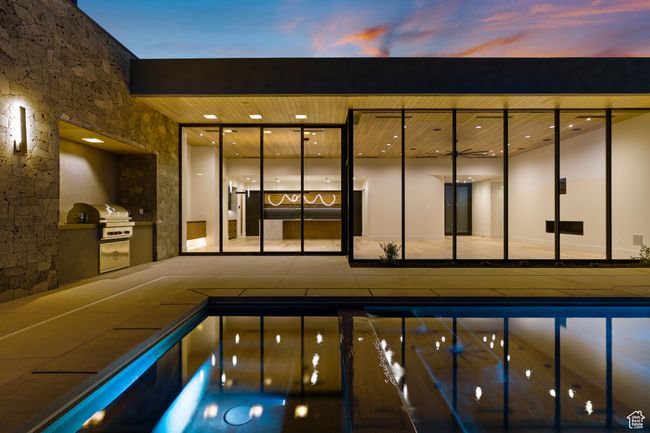 Pool at dusk featuring a grill and exterior kitchen | Image 14