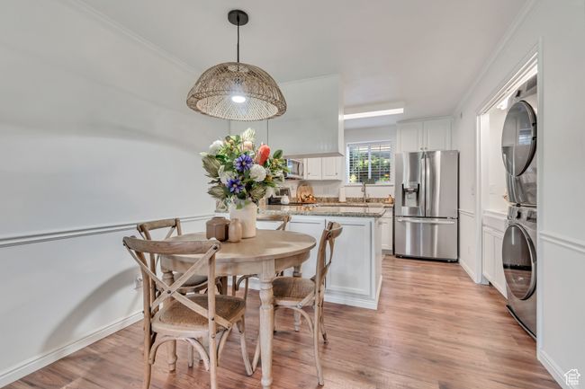 Dining area featuring stacked washer and clothes dryer, light wood finished floors, and ornamental molding | Image 4