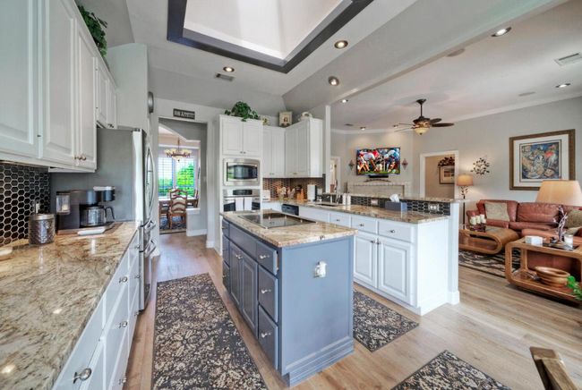 Kitchen with appliances with stainless steel finishes, white cabinetry, and light wood-style floors | Image 10