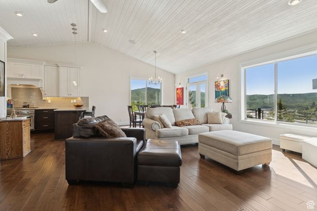 Living room featuring lofted ceiling, dark wood finished floors, a chandelier, a ceiling fan, and a mountain view | Image 13