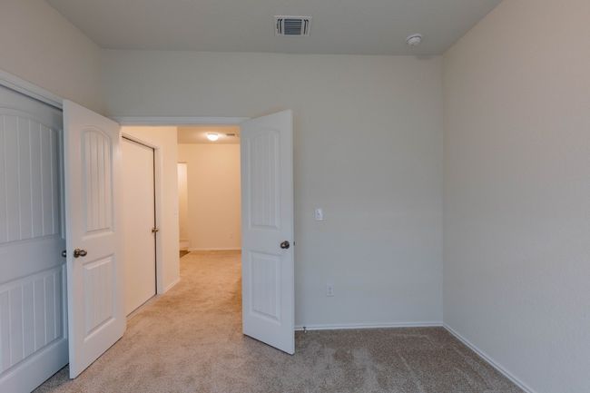 Empty room featuring light colored carpet, baseboards, and a smoke detector | Image 13