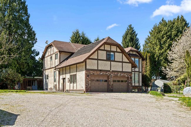 Tudor home with a garage, gravel driveway, and stucco siding | Image 4