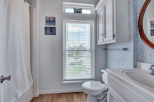 Charming first-floor bathroom features natural light, a full tub/shower combo, and crisp blue accents for a bright, coastal feel. Perfect for guests or convenient access from the main living area. | Image 9
