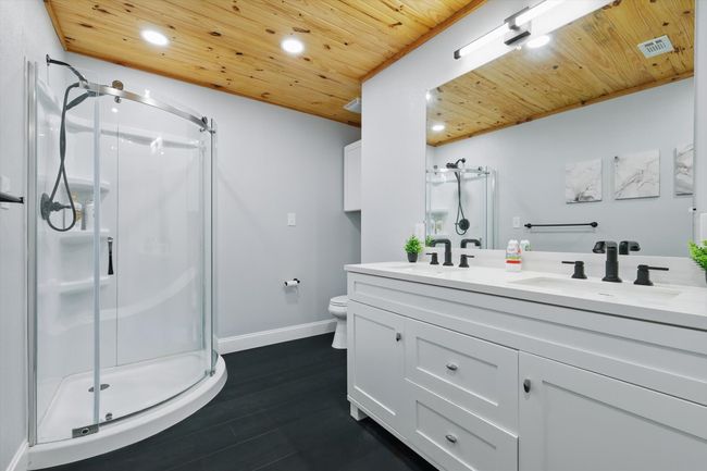 Bathroom with wooden ceiling, visible vents, a sink, and a shower stall | Image 30