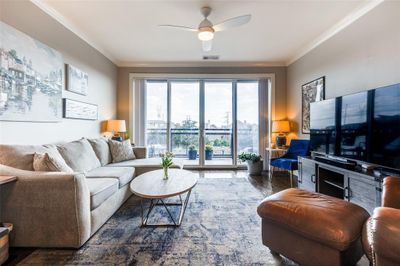 Living room with crown molding, ceiling fan, and dark wood-type flooring | Image 3