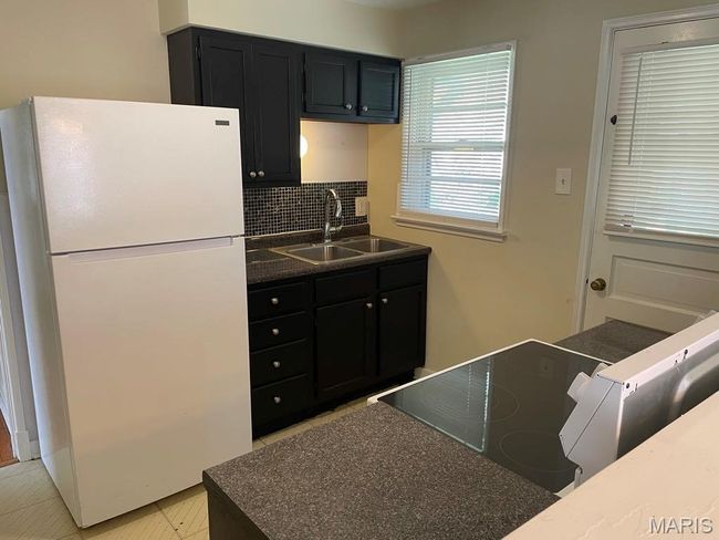 Kitchen with dark countertops, dark cabinetry, a sink, freestanding refrigerator, and tasteful backsplash | Image 9