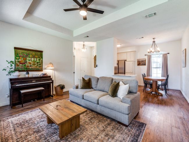 Living area with a chandelier, wood finished floors, ceiling fan, and a raised ceiling | Image 4