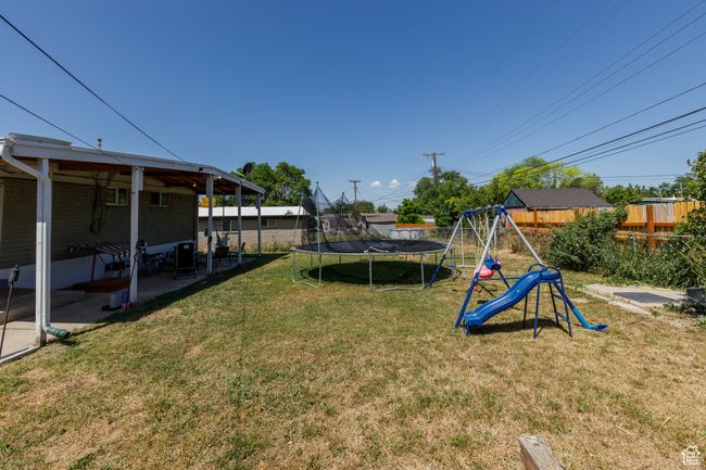 Fenced backyard featuring a trampoline, a playground, and a patio | Image 27