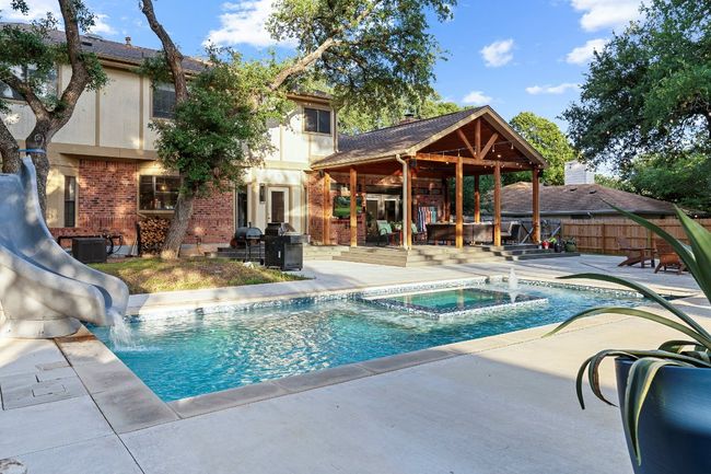View of swimming pool with a patio, a water slide, a pool with connected hot tub, and a grill | Image 36