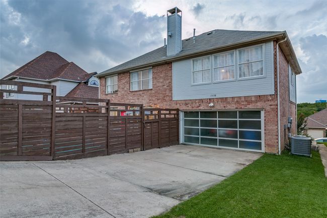 Rear view of house with central AC, concrete driveway, an attached garage, brick siding, and a chimney | Image 25