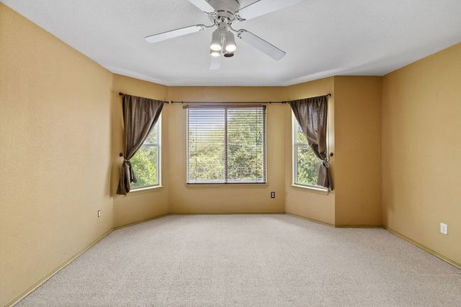 Carpeted empty room featuring baseboards and a ceiling fan | Image 26