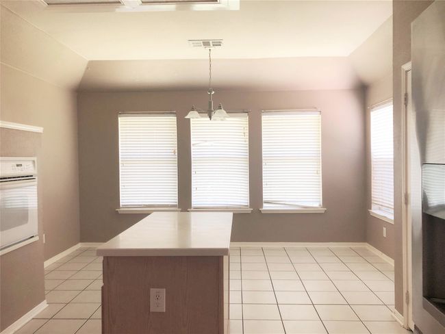 Kitchen featuring white oven, light tile patterned floors, healthy amount of natural light, and decorative light fixtures | Image 7