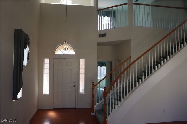 Foyer with a high ceiling, wood finished floors, stairway, plenty of natural light, and a chandelier | Image 19