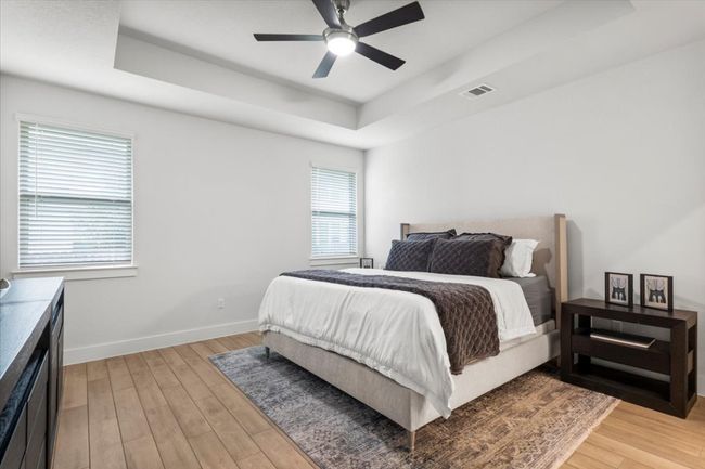 Bedroom with a tray ceiling, light wood-type flooring, and a ceiling fan | Image 12