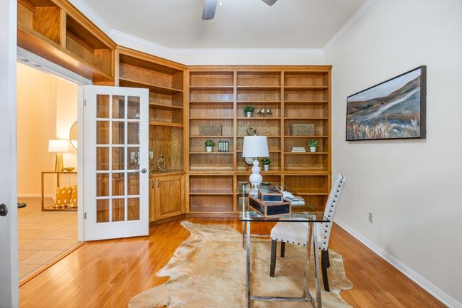 With tall ceilings, a ceiling fan, and a wall of custom shelving and cabinetry—the built-in bookshelves include space for a TV. | Image 21