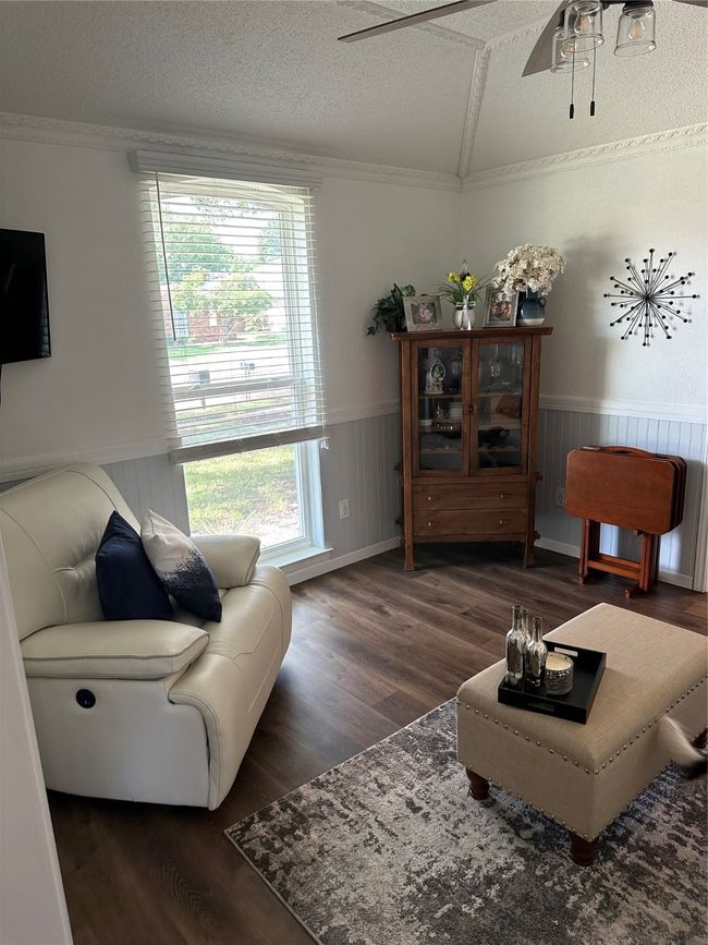 Living area with crown molding, wainscoting, wood finished floors, healthy amount of natural light, and a ceiling fan | Image 11
