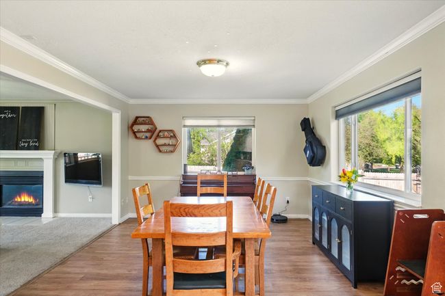 Dining space featuring ornamental molding, wood finished floors, a glass covered fireplace, and baseboards | Image 6