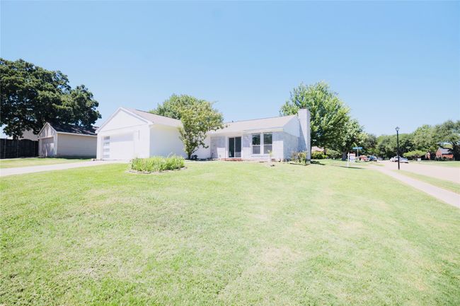 Ranch-style house with concrete driveway, a front lawn, and a chimney | Image 33
