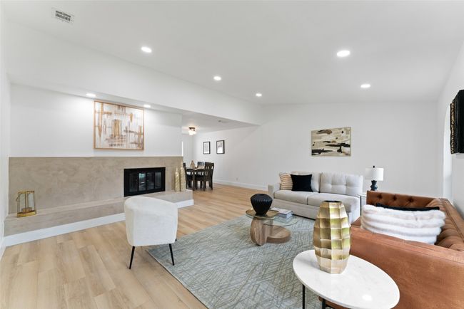 Living room featuring light wood-style floors, recessed lighting, and a fireplace | Image 4