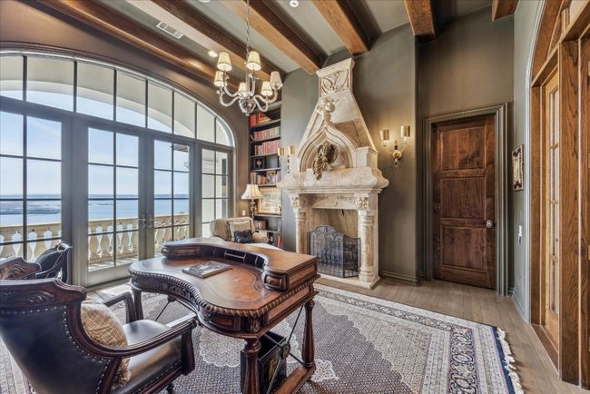 This handsomely appointed office with a double door entrance offers sweeping lake vistas, custom stone fireplace, beamed ceiling and built ins. | Image 25