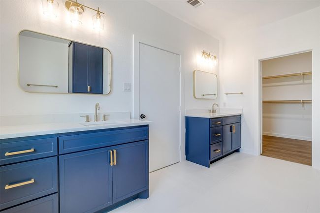 Bathroom with two vanities, visible vents, a sink, and a walk in closet | Image 18