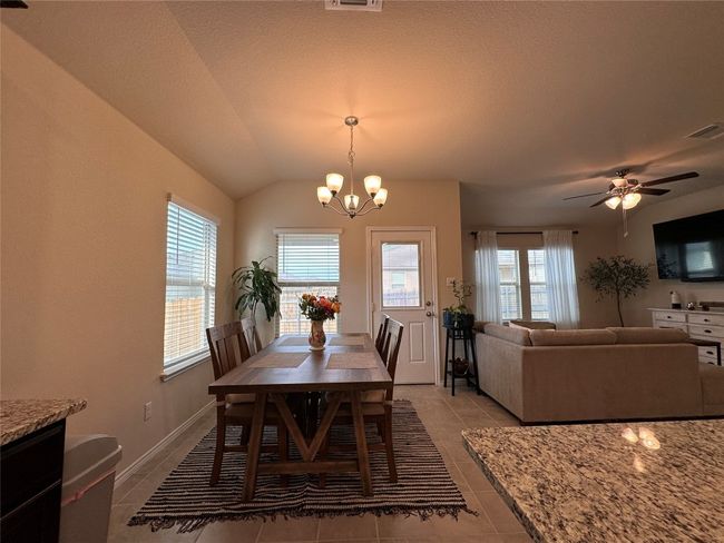 Dining space featuring lofted ceiling, a chandelier, light tile patterned floors, a ceiling fan, and baseboards | Image 24