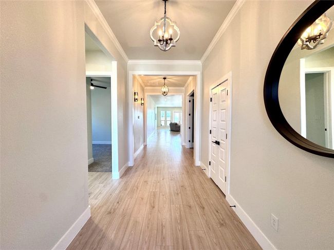 Hall with a chandelier, light wood finished floors, and crown molding | Image 4