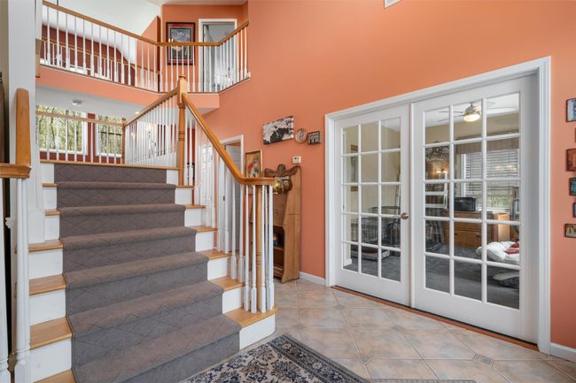Staircase with baseboards, ceiling fan, tile patterned floors, and a towering ceiling | Image 13