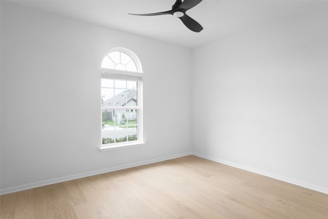 Bright, roomy bedroom with charming arched window detail. | Image 23