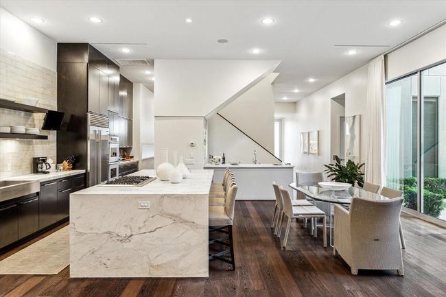 A view from the Family Room looking toward the Kitchen and Wet Bar which is positioned against the Staircase wall. The clean lines of the minimalist design evokes the modern style at its best. | Image 12