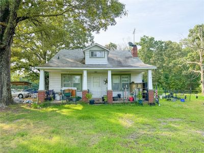 View of front facade with a carport, a porch, and a front yard | Image 1